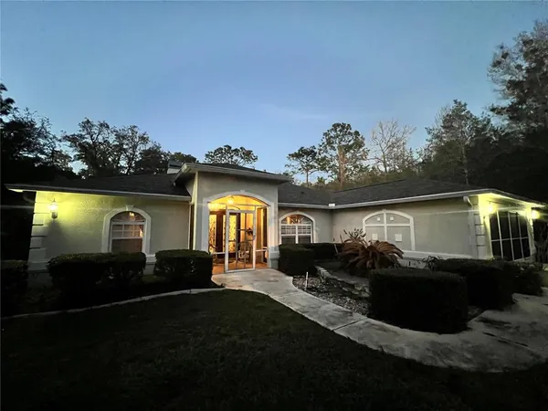 a view of house with yard outdoor seating and covered with trees