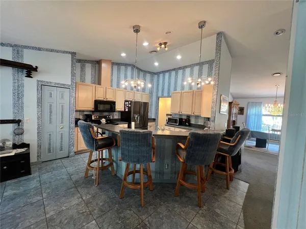 a large kitchen with a table chairs refrigerator and microwave