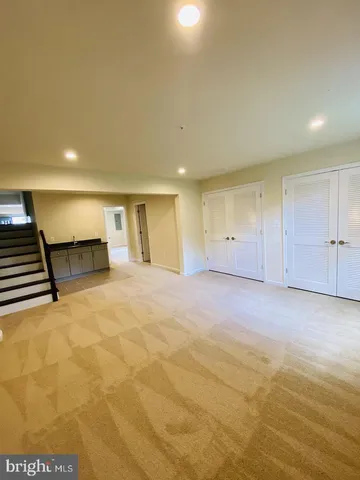 a view of an empty room with wooden floor and a kitchen