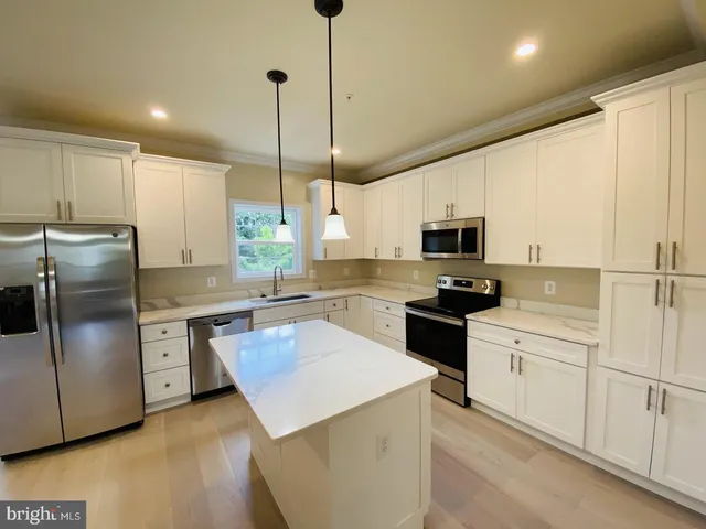 a kitchen with stainless steel appliances granite countertop a refrigerator a sink dishwasher a stove and white cabinets with wooden floor