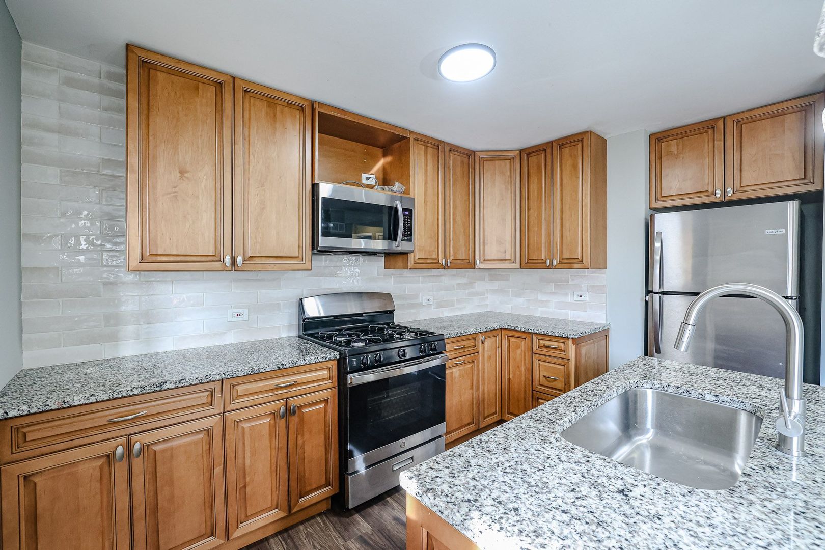 746 Walnut Street, Unit 2E Waukegan, IL 60085 - Photo 4 of 10 a kitchen with stainless steel appliances granite countertop a sink stove microwave and refrigerator