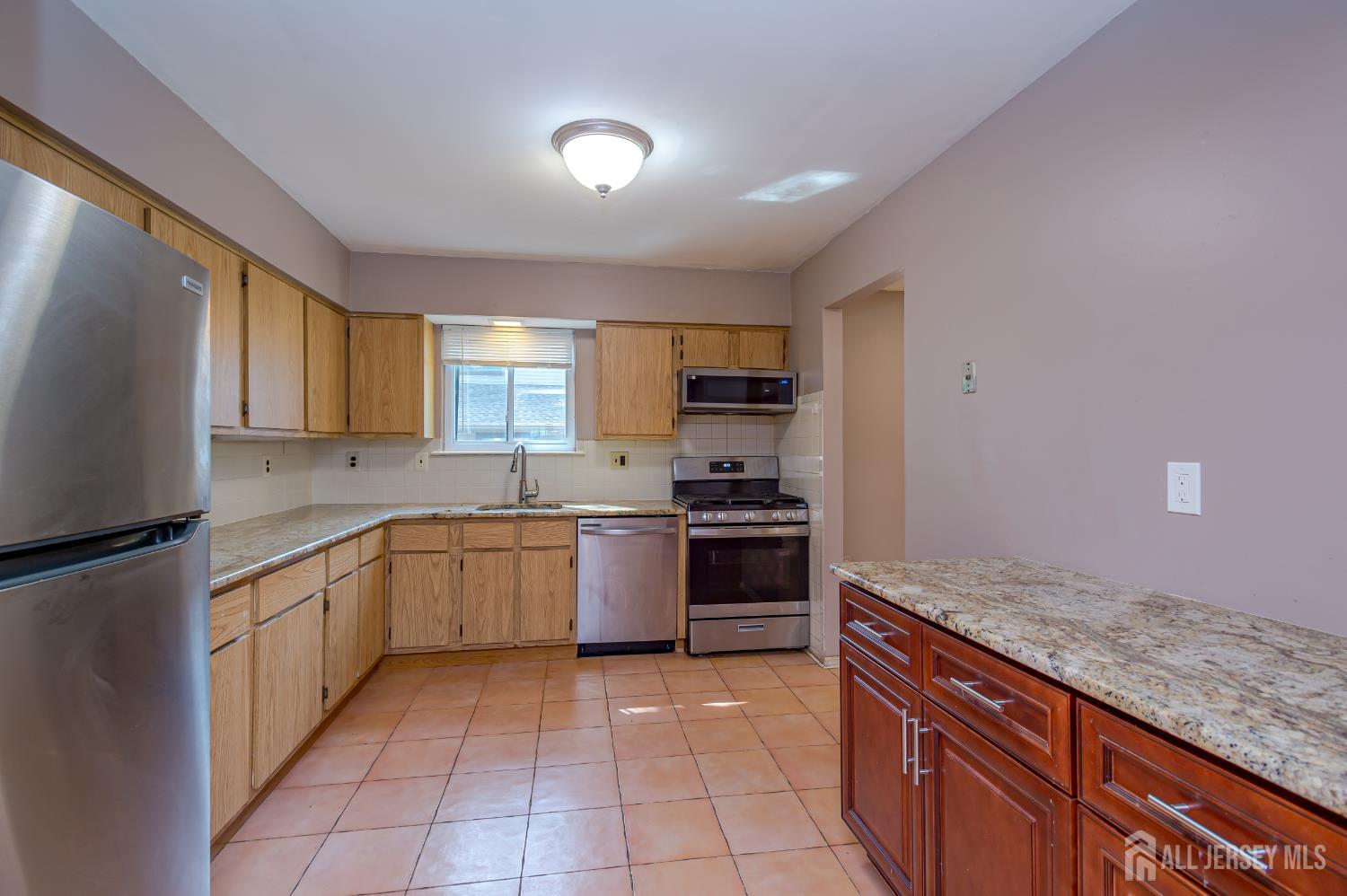 5601 Hana Road Edison, NJ 08817 - Photo 12 of 27 a large kitchen with granite countertop a stove sink and cabinets