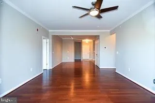 a view of an empty room with window a ceiling fan and wooden floor