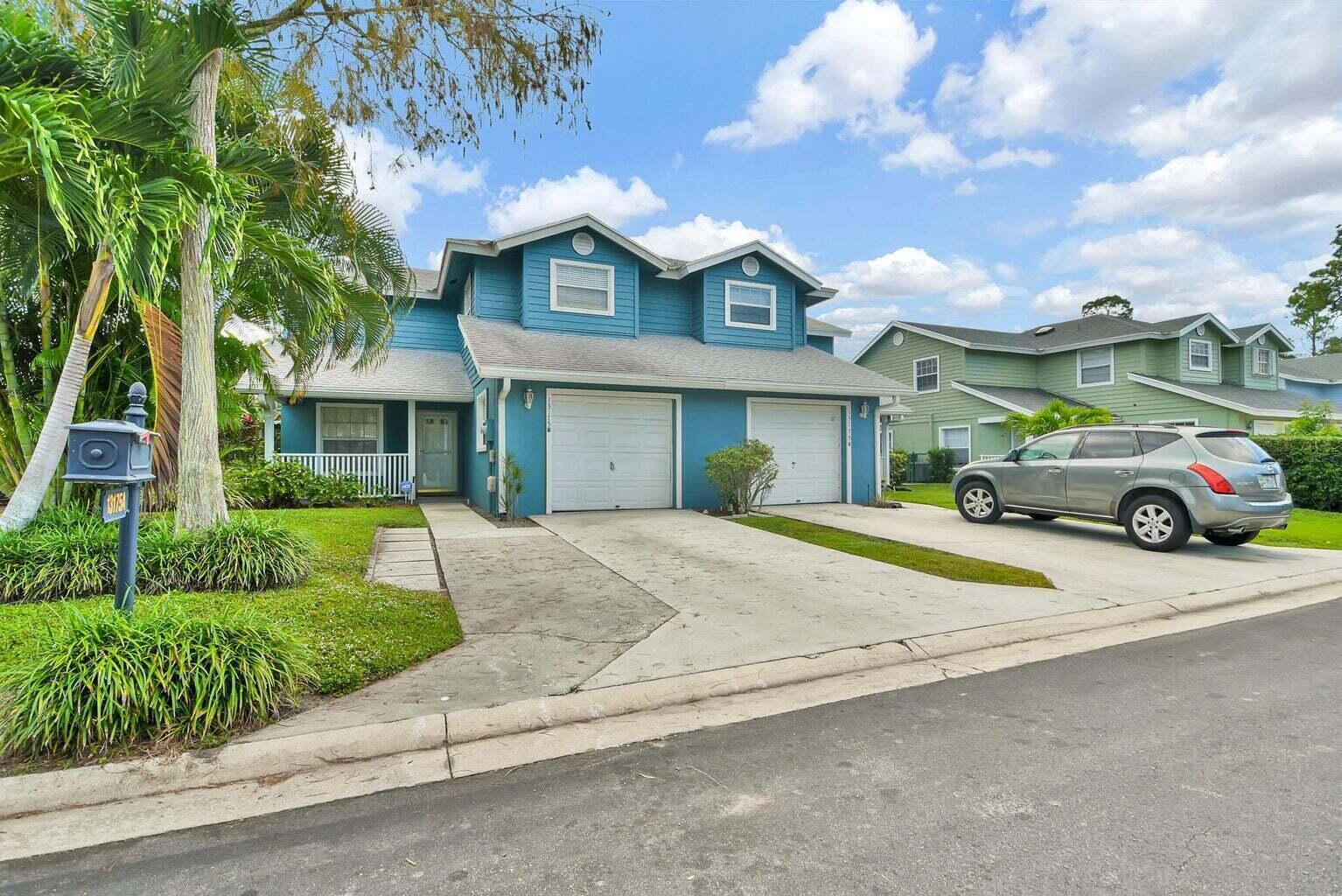13175 Quiet Woods Road, Unit A Wellington, FL 33414 - Photo 2 of 46 a front view of a house with a yard and garage