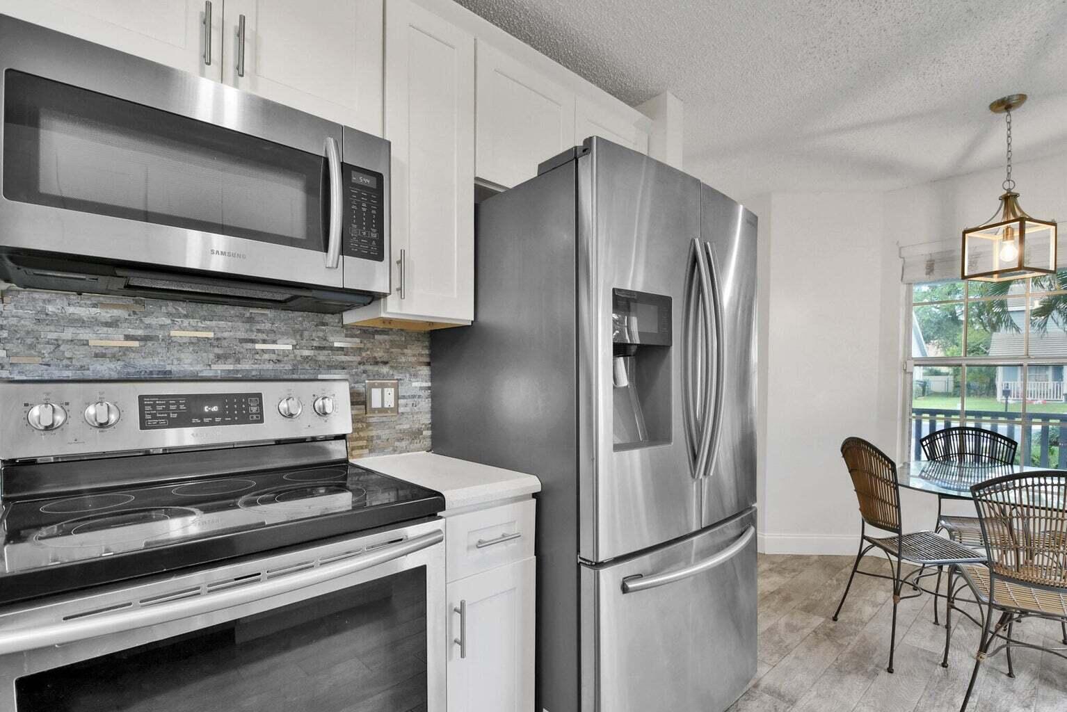 13175 Quiet Woods Road, Unit A Wellington, FL 33414 - Photo 21 of 46 a kitchen with stainless steel appliances granite countertop a refrigerator microwave and stove top oven
