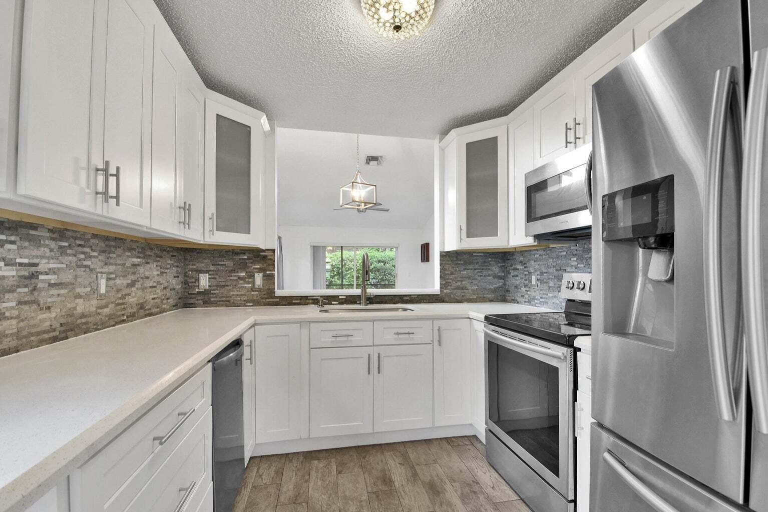 13175 Quiet Woods Road, Unit A Wellington, FL 33414 - Photo 22 of 46 a kitchen with cabinets appliances a sink and a counter top