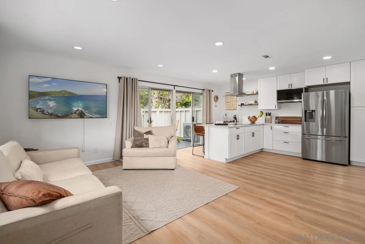 751 Pyramid Point Way Oceanside, CA 92058 - Photo 3 of 30 a large white kitchen with stainless steel appliances granite countertop a stove a refrigerator a oven with white cabinets and wooden floor