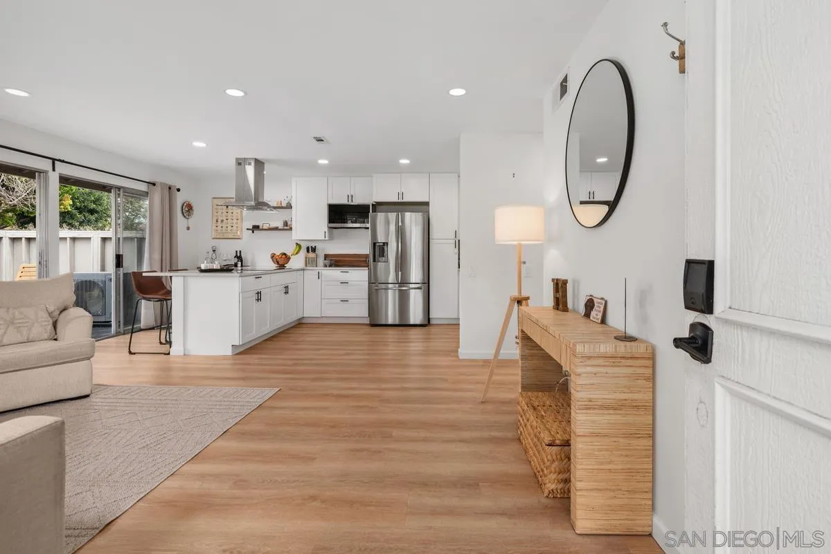 751 Pyramid Point Way Oceanside, CA 92058 - Photo 4 of 30 a large white kitchen with stainless steel appliances granite countertop a stove a refrigerator a oven with white cabinets and wooden floor