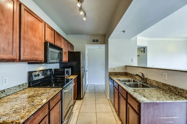 a kitchen with stainless steel appliances granite countertop a stove a sink and a refrigerator