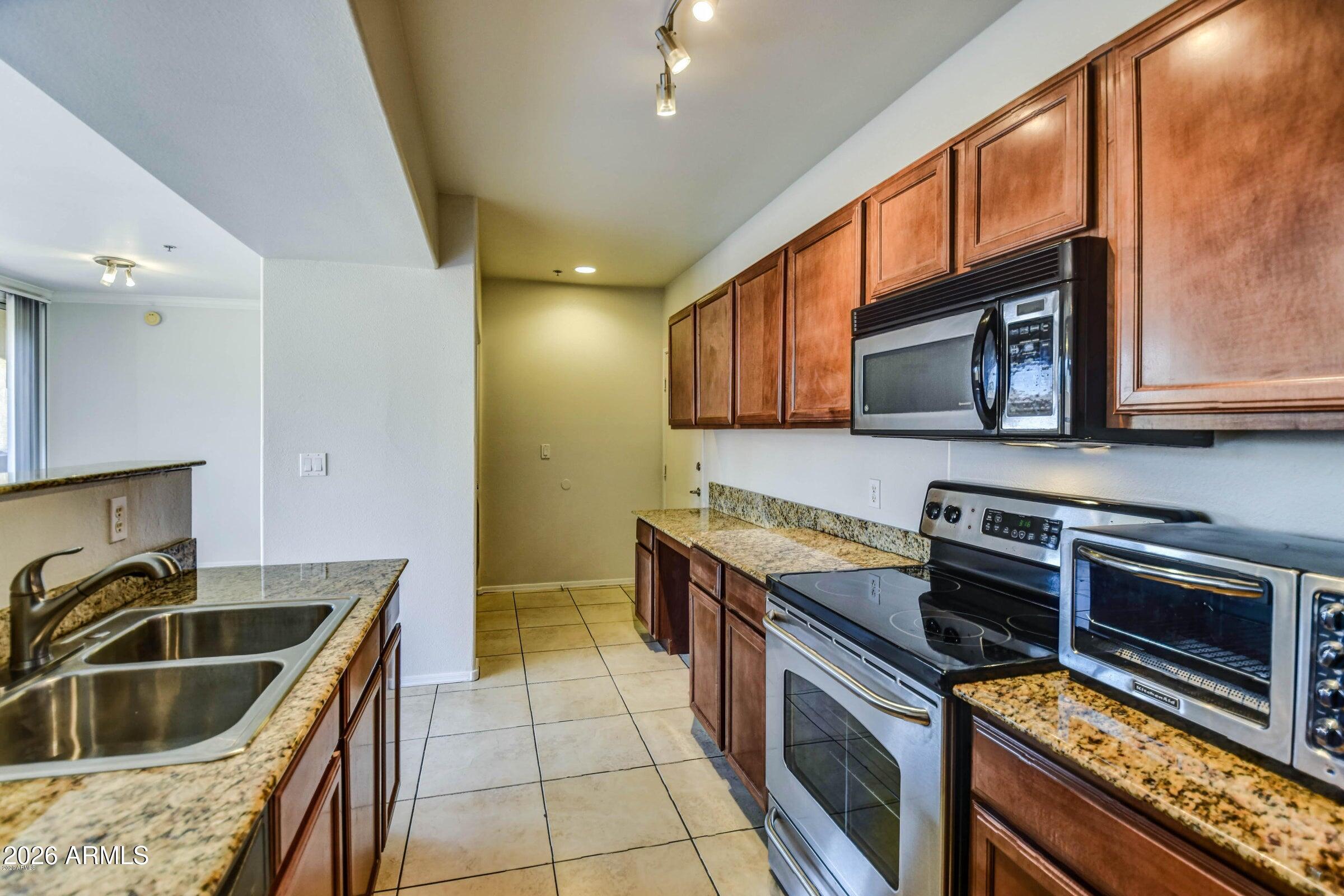 2134 East Broadway Road, Unit 1039 Tempe, AZ 85282 - Photo 13 of 24 a kitchen with stainless steel appliances granite countertop a sink stove and microwave