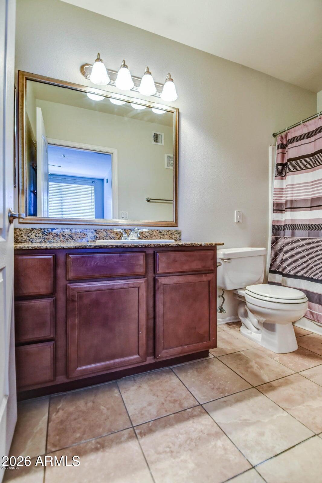 2134 East Broadway Road, Unit 1039 Tempe, AZ 85282 - Photo 19 of 24 a bathroom with a toilet a sink and mirror