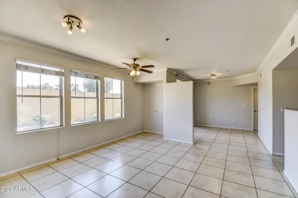 a view of an empty room with window and chandelier fan