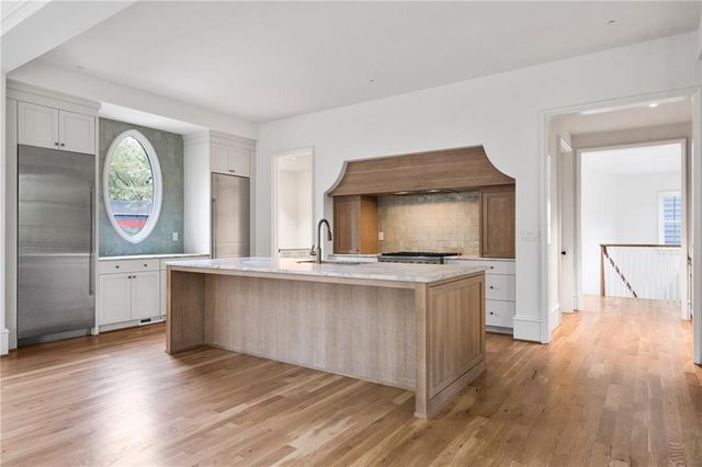 a living room with stainless steel appliances granite countertop furniture a wooden floor and a window