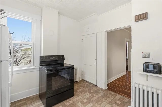 a view of kitchen and empty room with a fireplace