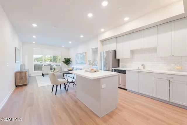 a kitchen with a table chairs wooden floors and white stainless steel appliances