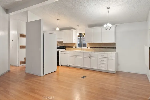 a kitchen with stainless steel appliances granite countertop a stove a sink and a refrigerator with wooden floors