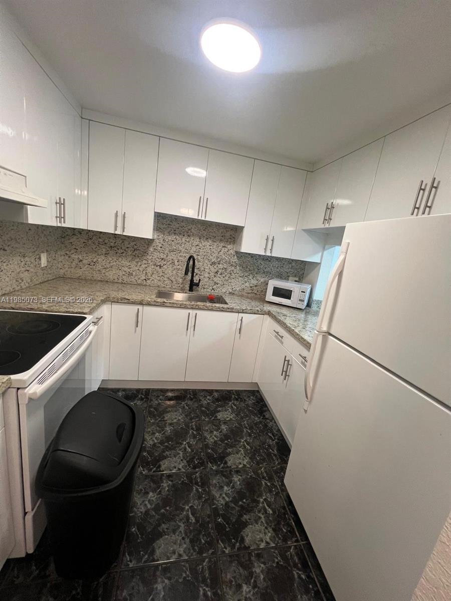 1900 West 68th Street, Unit D207 Hialeah, FL 33014 - Photo 17 of 33 a kitchen with a sink a toilet and cabinets
