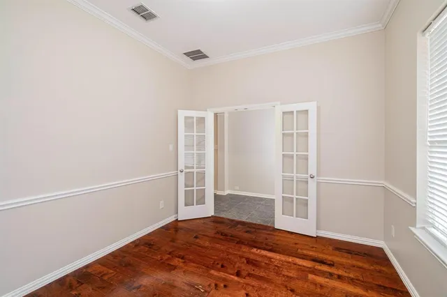 a view of an empty room with wooden floor and window