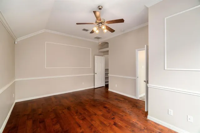 an empty room with a ceiling fan and wooden floor