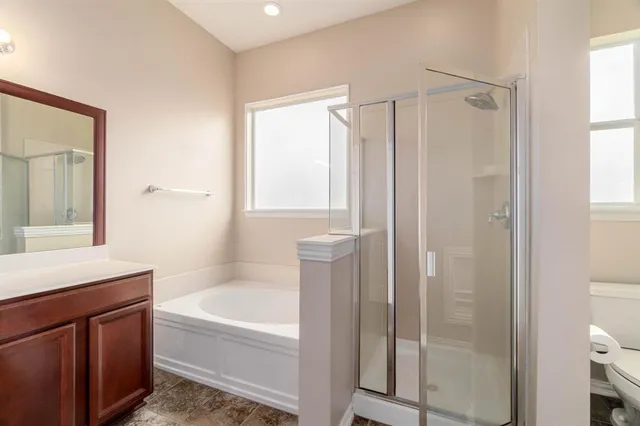 a bathroom with a bathtub a mirror a vanity and a shower