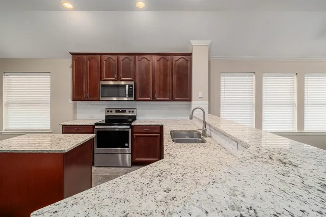 a kitchen with granite countertop wooden cabinets a stove top oven a sink and dishwasher