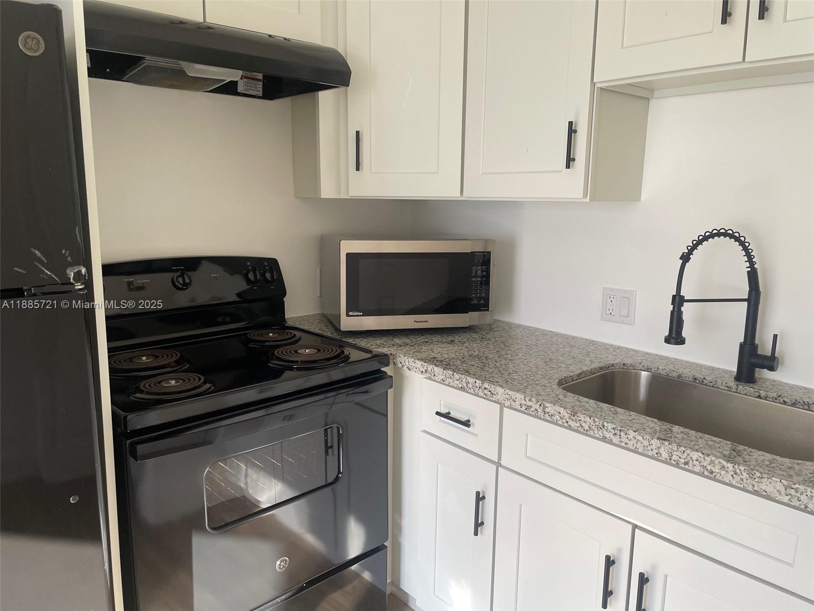 2434 Coolidge Street, Unit FRONT Hollywood, FL 33020 - Photo 10 of 18 a kitchen with granite countertop a stove and a sink