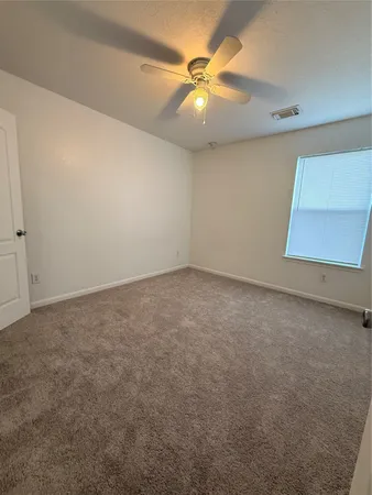 an empty room with a chandelier fan and windows