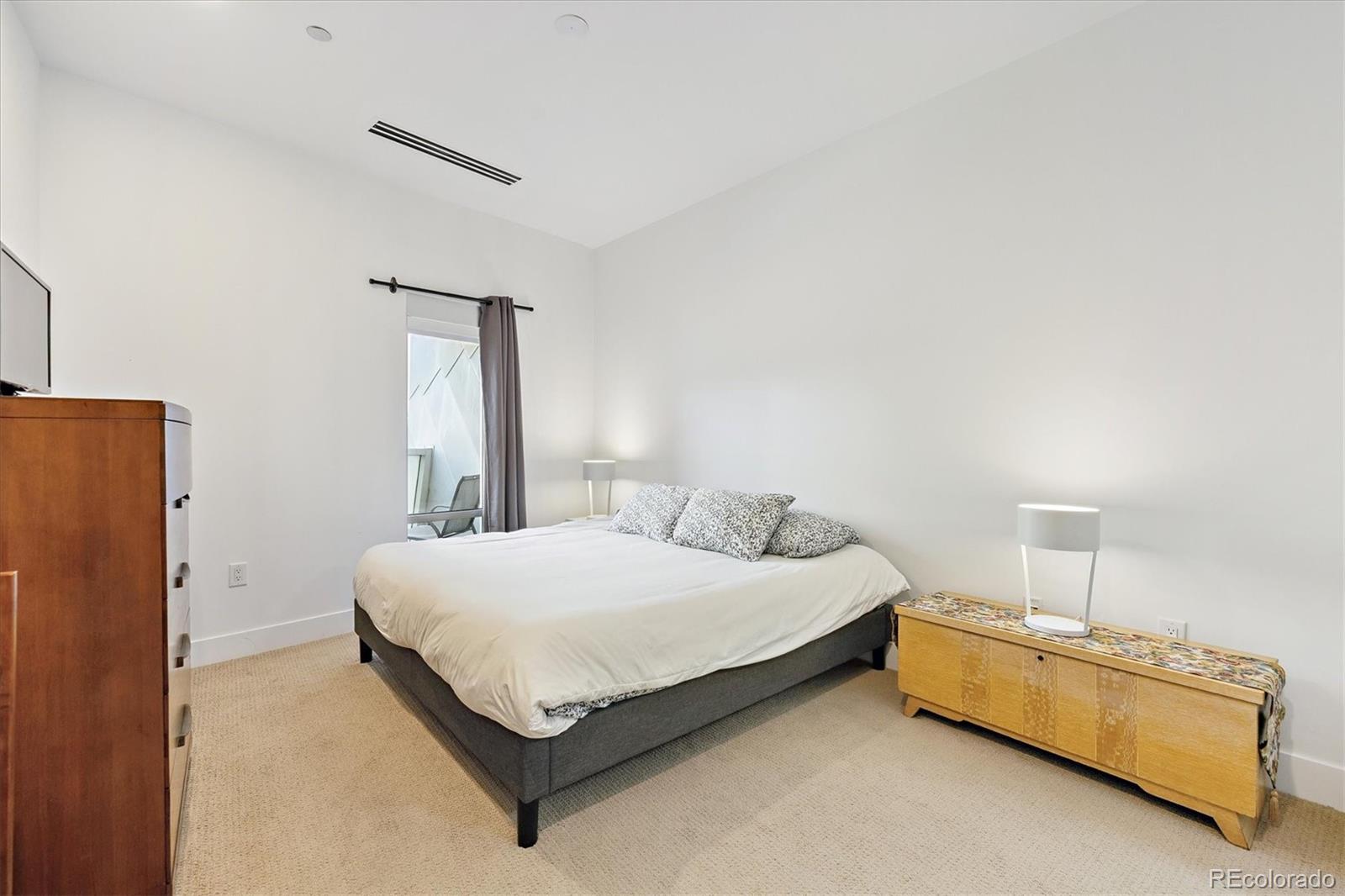 1200 Acoma Street, Unit 303 Denver, CO 80204 - Photo 16 of 48 a bedroom with a bed and a refrigerator