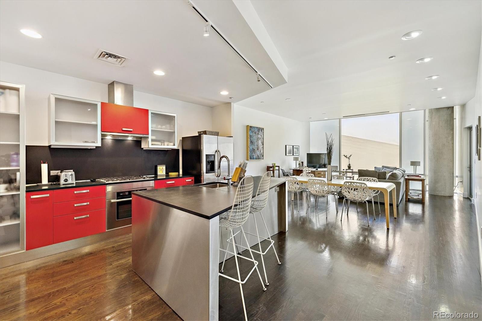 1200 Acoma Street, Unit 303 Denver, CO 80204 - Photo 5 of 48 a kitchen with stainless steel appliances granite countertop a stove top oven a sink a dining table and chairs with wooden floor