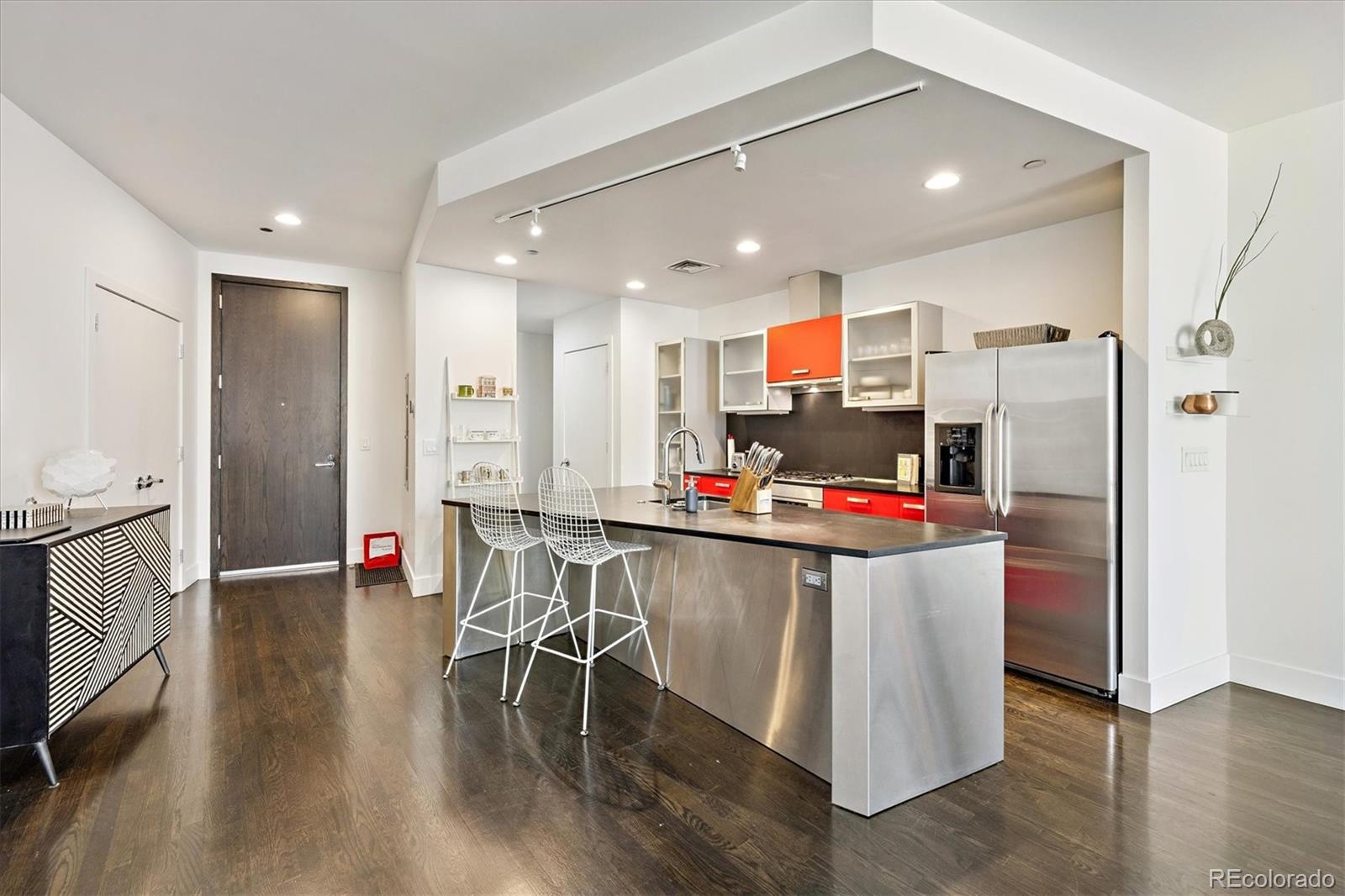 1200 Acoma Street, Unit 303 Denver, CO 80204 - Photo 9 of 48 a kitchen with stainless steel appliances a dining table chairs refrigerator and sink