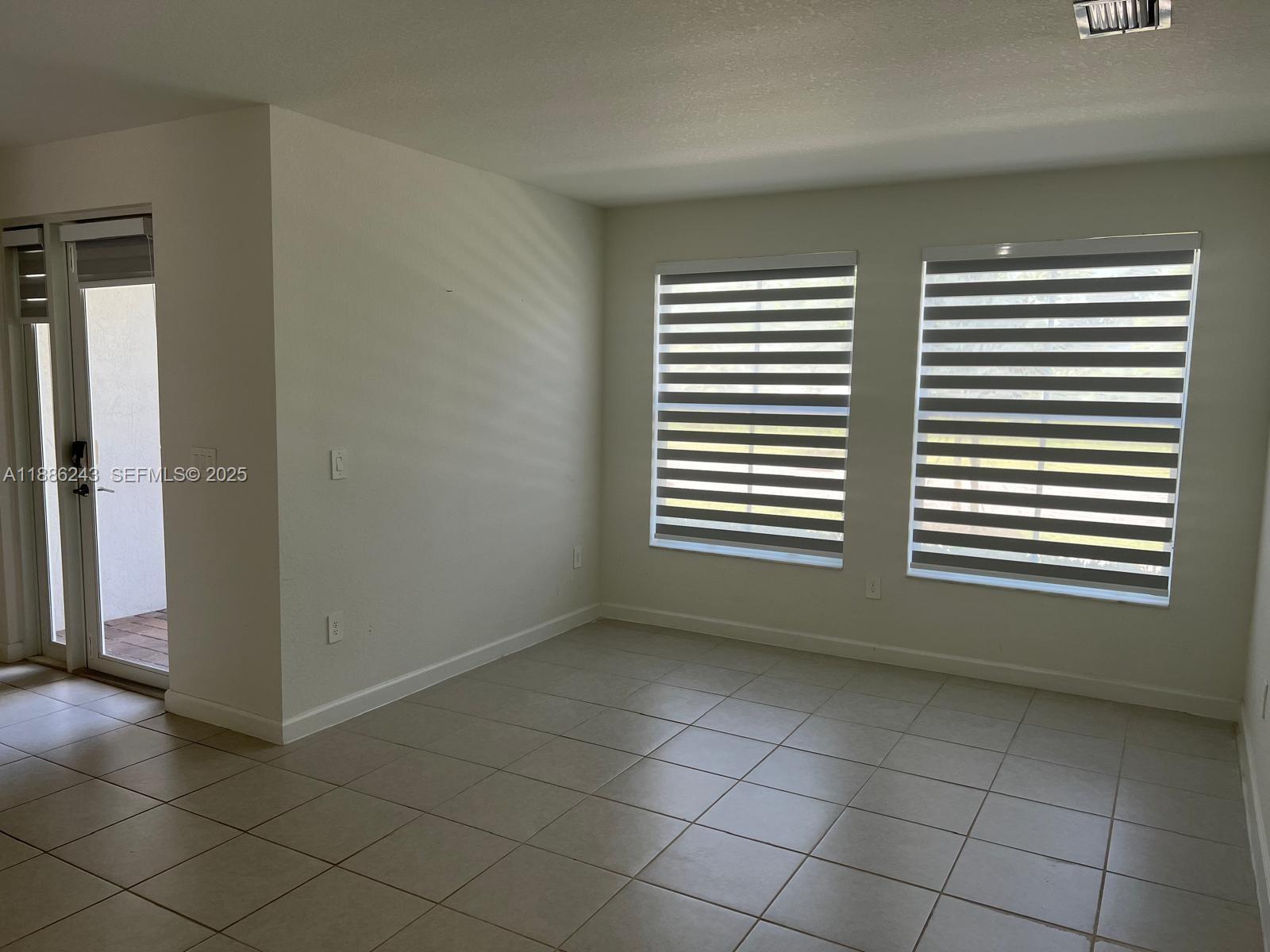 26413 Southwest 149th Avenue, Unit 26413 Homestead, FL 33032 - Photo 5 of 29 an empty room with a chair and a window