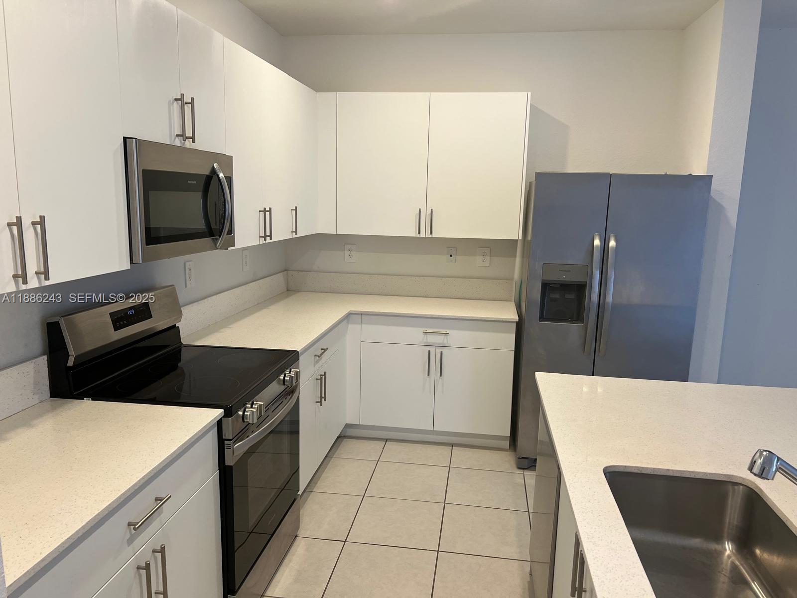 26413 Southwest 149th Avenue, Unit 26413 Homestead, FL 33032 - Photo 8 of 29 a kitchen with a sink a microwave a stove and refrigerator