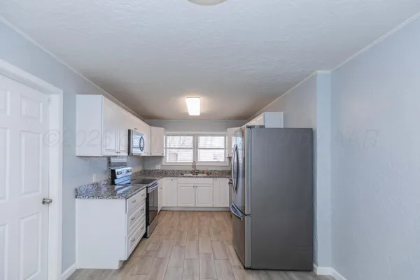 a kitchen with granite countertop white cabinets and a sink