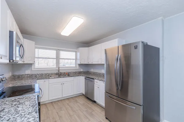 a kitchen with stainless steel appliances granite countertop a refrigerator stove and sink