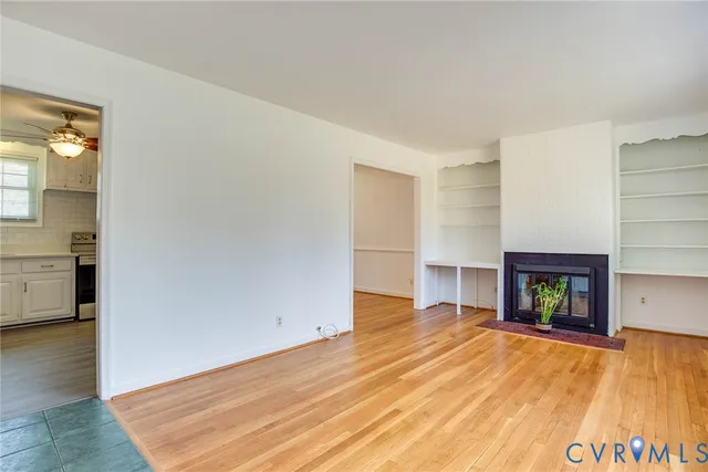 a view of empty room with wooden floor and fireplace