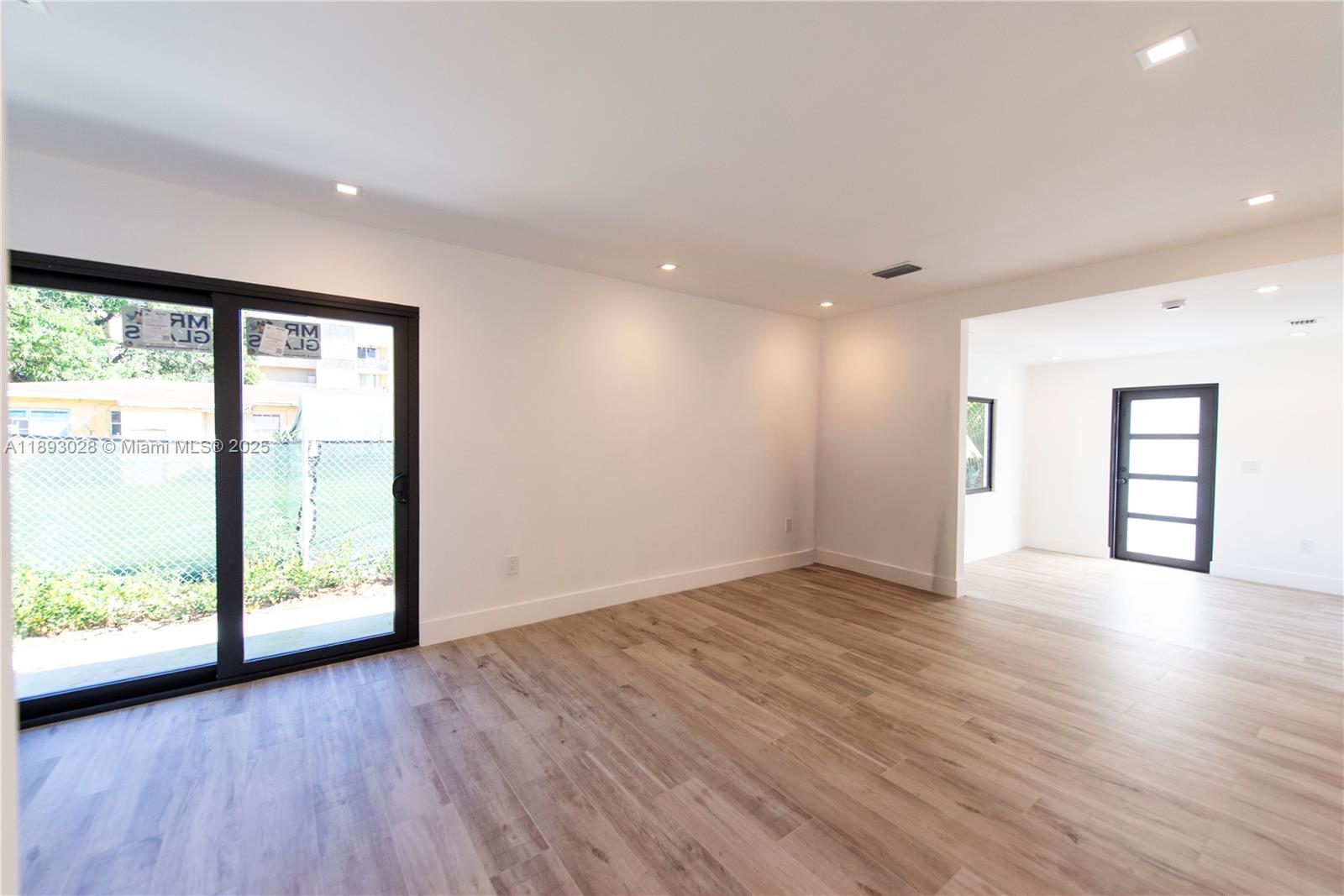 764 Northwest 36th Avenue, Unit 1 Miami, FL 33125 - Photo 11 of 17 a view of an empty room with wooden floor and a window