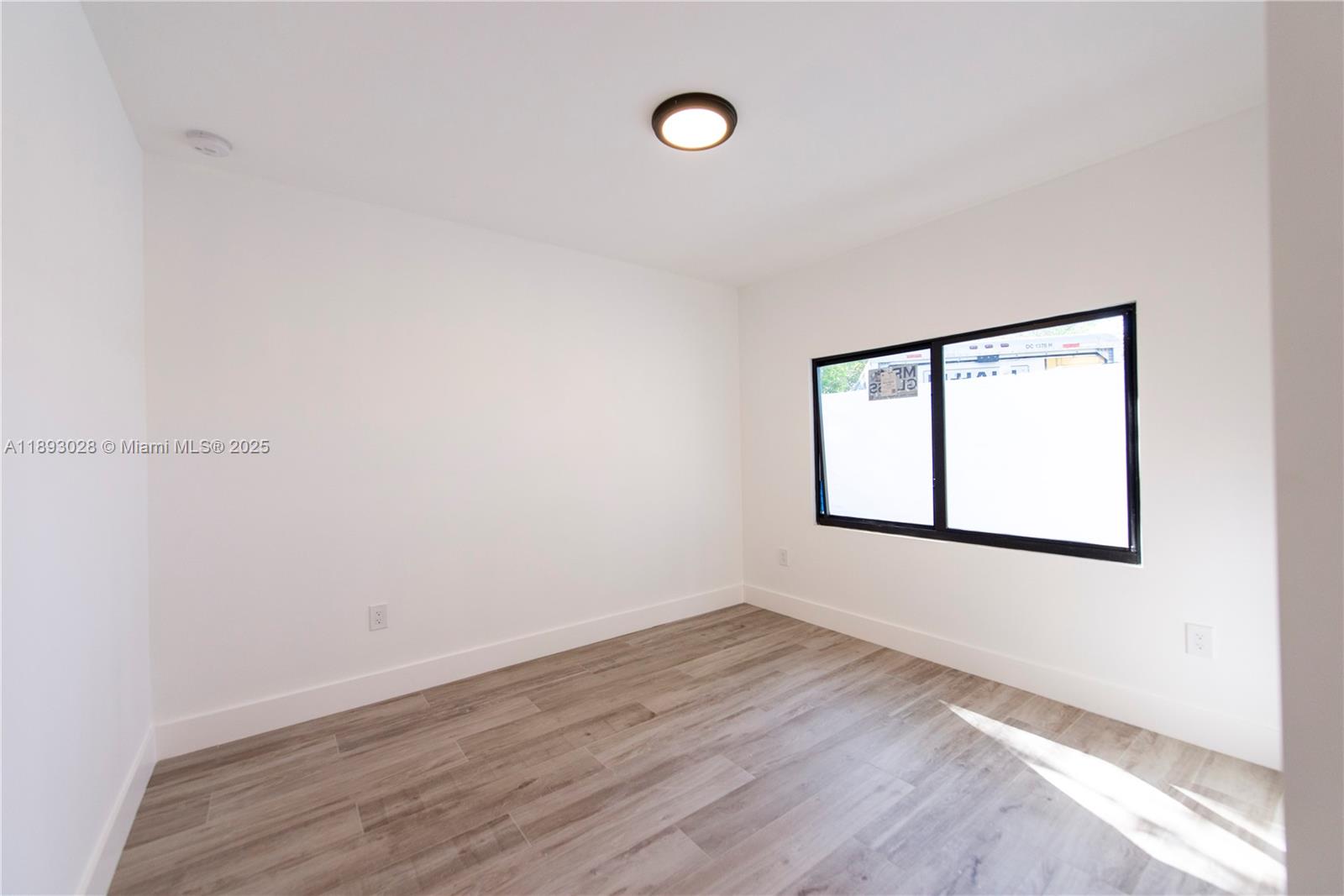 764 Northwest 36th Avenue, Unit 1 Miami, FL 33125 - Photo 12 of 17 an empty room with wooden floor and windows
