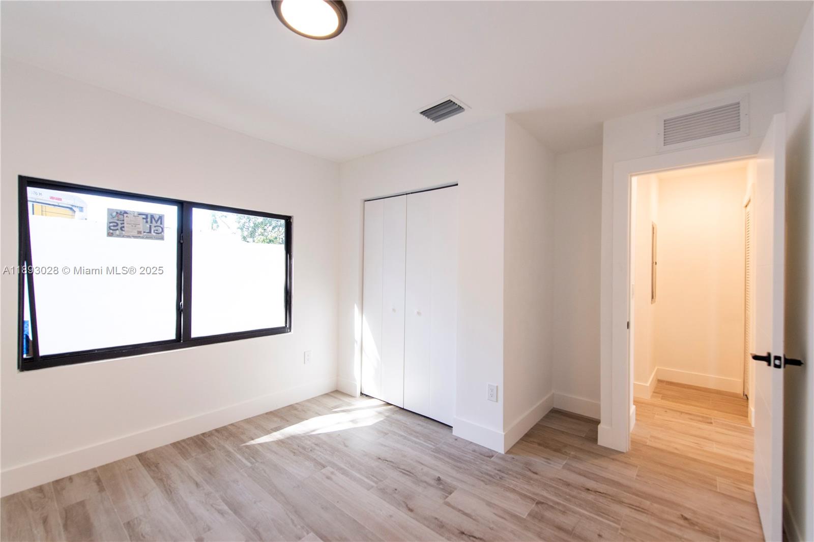 764 Northwest 36th Avenue, Unit 1 Miami, FL 33125 - Photo 13 of 17 a view of an empty room with wooden floor and a window