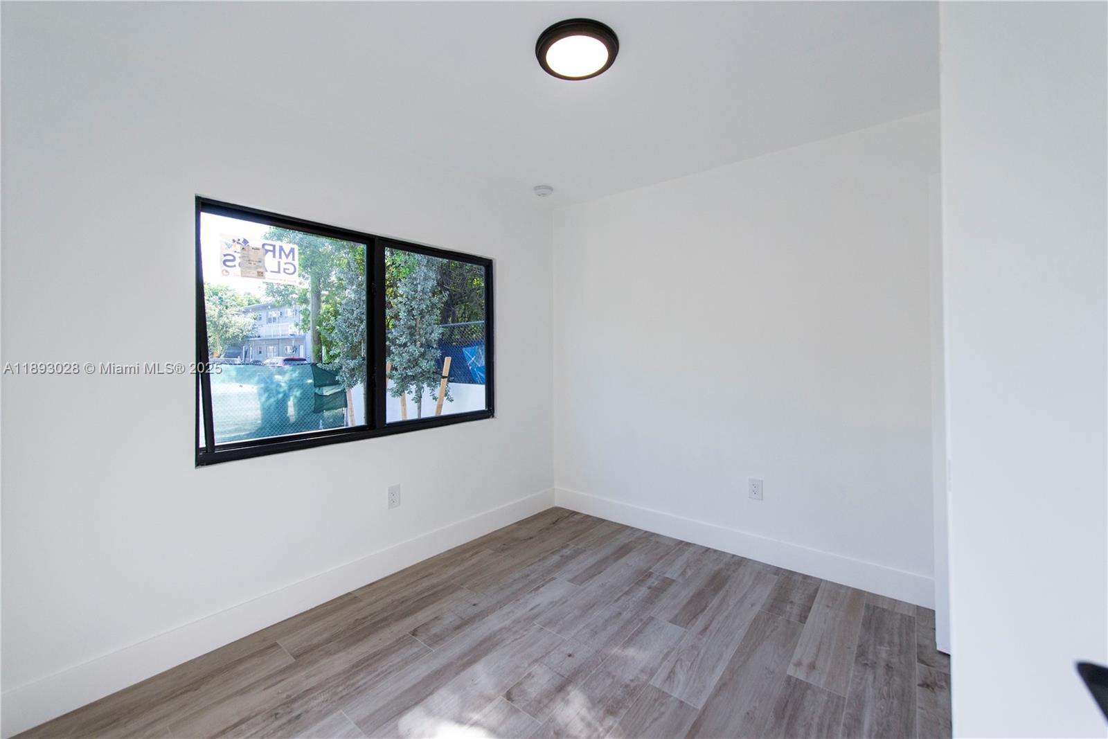 764 Northwest 36th Avenue, Unit 1 Miami, FL 33125 - Photo 3 of 17 an empty room with wooden floor and windows