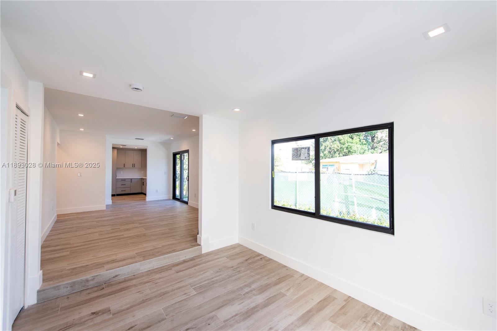 764 Northwest 36th Avenue, Unit 1 Miami, FL 33125 - Photo 5 of 17 a view of an empty room with wooden floor and a window