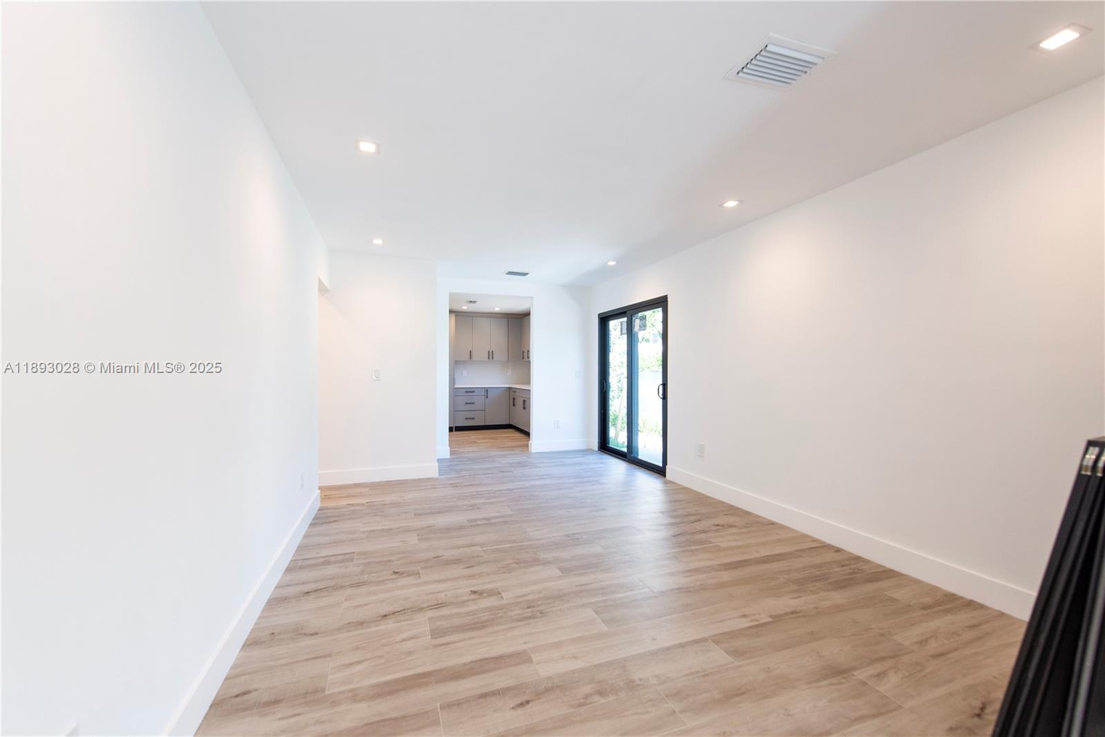 764 Northwest 36th Avenue, Unit 1 Miami, FL 33125 - Photo 6 of 17 a view of an empty room with wooden floor and a window