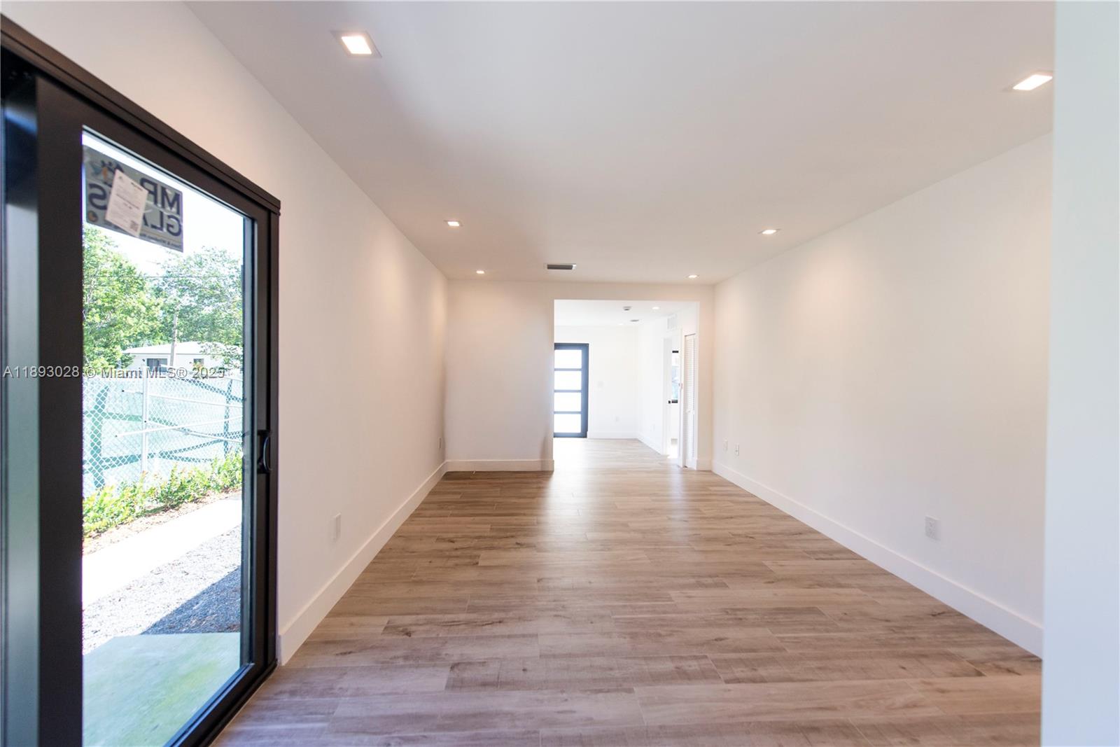 764 Northwest 36th Avenue, Unit 1 Miami, FL 33125 - Photo 10 of 17 a view of an empty room with wooden floor and a window
