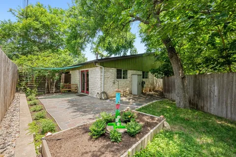 a view of a backyard with potted plants and large tree