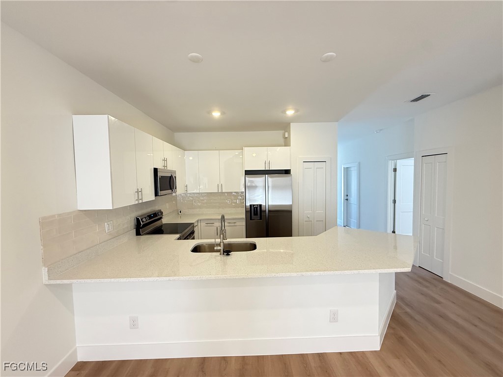 4719 28th Street Southwest Lehigh Acres, FL 33973 - Photo 3 of 13 a large white kitchen with kitchen island a sink a refrigerator and a stove