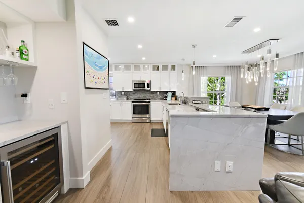 a kitchen with stainless steel appliances granite countertop a refrigerator a stove top oven a sink dishwasher and white cabinets with wooden floor