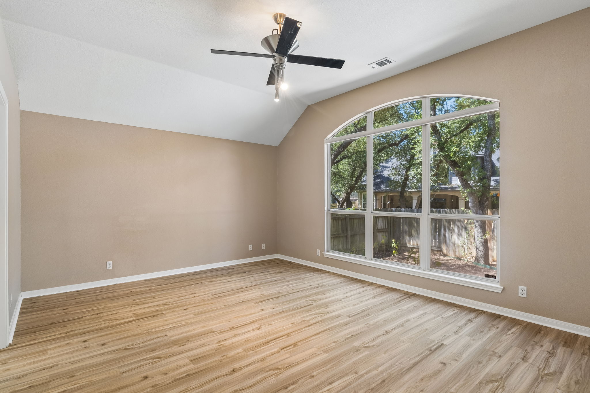 15814 Rustic Lane Austin, TX 78717 - Photo 21 of 29 A spacious room features vaulted ceilings, rich wood floors, and a large arched picture window.