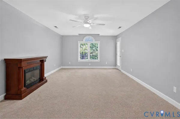 a view of an empty room with a chandelier fan