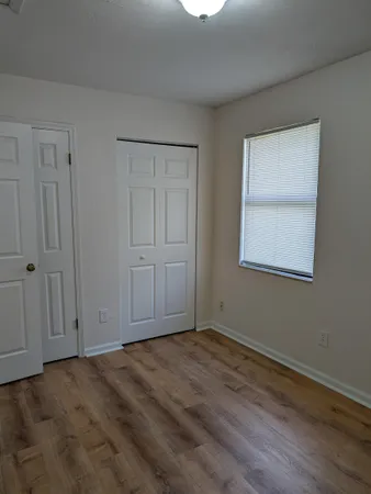 a view of an empty room with wooden floor and closet
