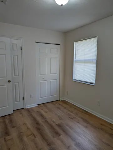 a view of an empty room with wooden floor and closet
