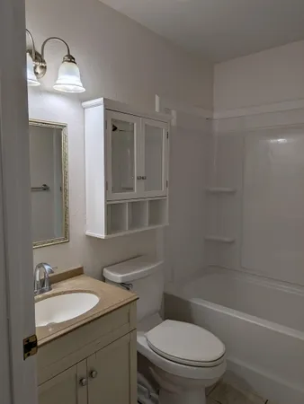 a bathroom with a sink toilet vanity granite tub and shower